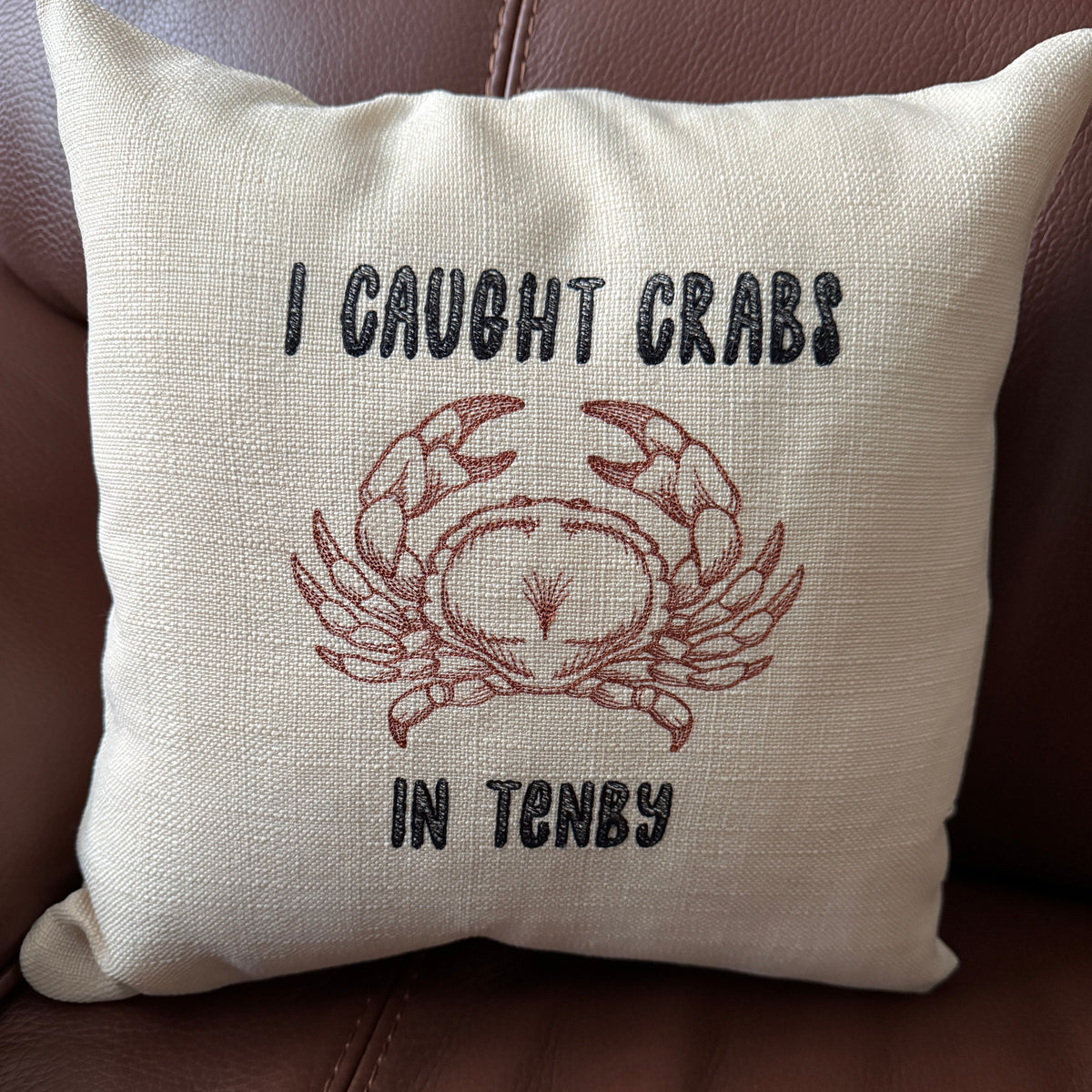 14 inch embroidered cushion reading I Caught Crabs in Tenby with a crab design on natural fabric