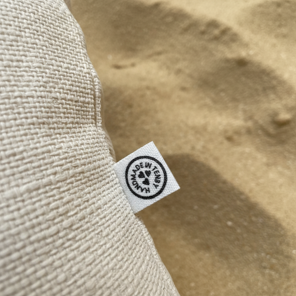 Handmade in Tenby label on sand background