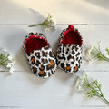 Leopard print baby shoes on white wood with flowers