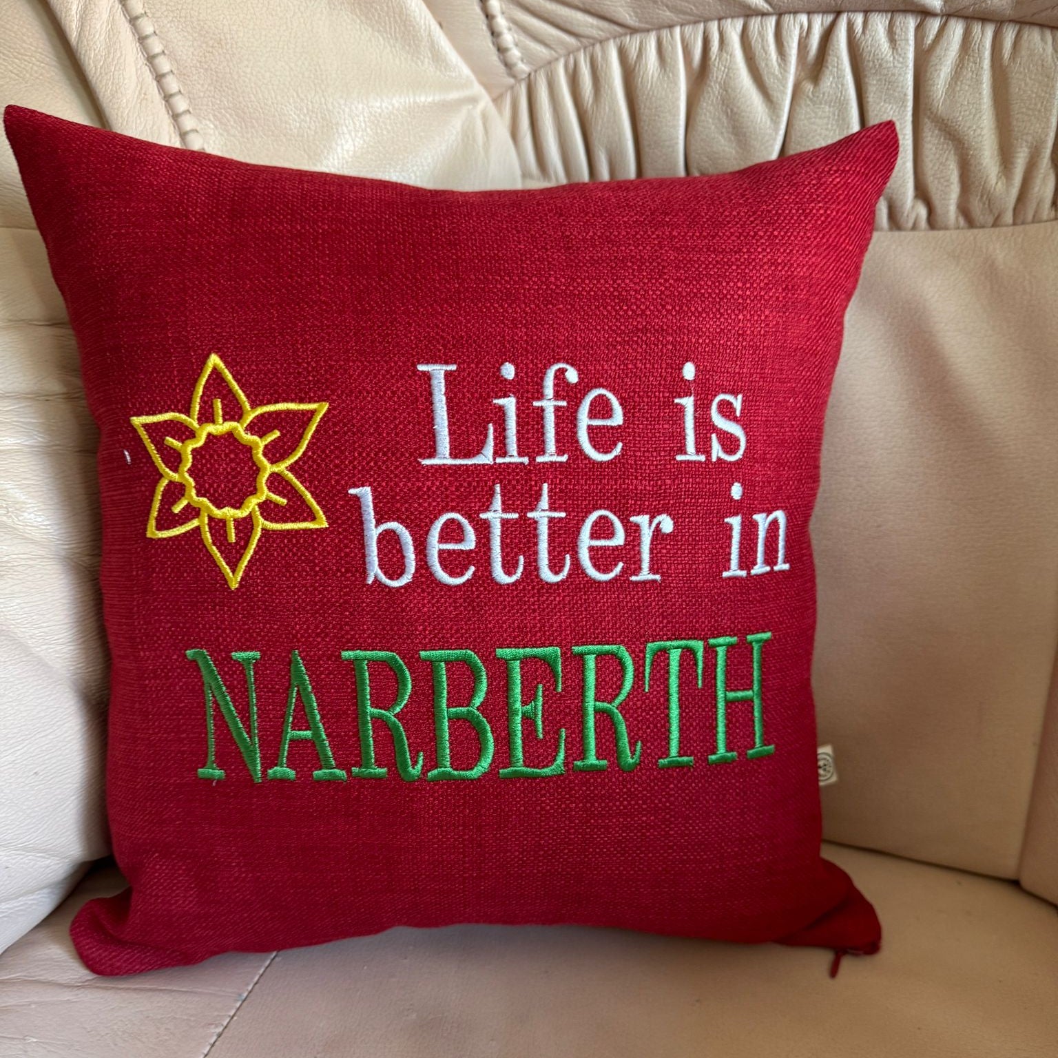14 inch red embroidered cushion reading Life is Better in Narberth with a gold Welsh daffodil motif